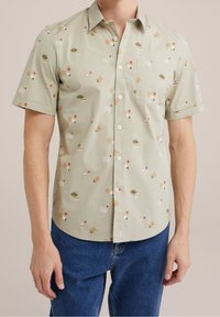 Krátký rukáv, světle zelená košile s květinovým a abstraktním vzorem, s náprsní kapsou a knoflíkovým zapínáním, vyrobená z bavlněné tkaniny.