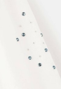 Biały materiał z rozproszonymi jasnoniebieskimi i przezroczystymi okrągłymi cyrkoniami o różnych rozmiarach, dodającymi teksturę i szczegóły powierzchni.