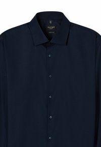 Navyblaue super-slim-fit Dressshirt aus strukturiertem Stoff. Verfügt über einen spitzen Kragen, sechs Knöpfe und ein Etikett mit Größeninformationen.