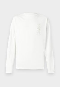 Μακρυμάνικο λευκό βαμβακερό T-shirt με μια μικρή εκτυπωμένη γραφική απεικόνιση σε ήπιους χρωματισμούς στο αριστερό στήθος και ένα λογότυπο στη γαζωμένη πλευρά του μανικιού.