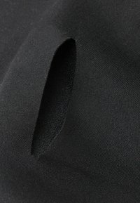 Černá látka s hladkým povrchem obsahuje výřez. Materiál vypadá elasticky a ukazuje čistý, minimalistický design.