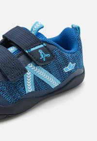Modré sportovní boty s texturovaným síťovaným svrškem. Obsahují suchý zip a gumovou podrážku. Akcenty ve světlejší modré barvě a logem.