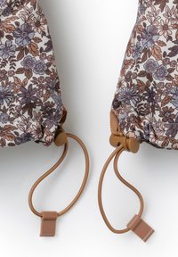 Blommiga dragspelsväskor i nyanser av brunt, blått och kräm; har ett mjukt tyg med texturerad finish och bruna snördetaljer.