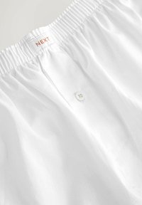 Weiße Baumwollshorts mit einem gerafften Gummibund, einem einzelnen Knopfverschluss und einem kleinen Etikett mit dem Markennamen "NEXT."