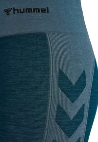 Hummels damträningsleggings i olika nyanser av teal. Har ett texturerat material med ribbade detaljer och ett stort chevronmönster.