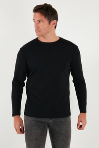 Juodas ilgomis rankovėmis marškinėliai, pagaminti iš medvilnės, su apvaliu kaklu, prigludusia forma, lygia tekstūra ir minimaliomis siuvimo detalėmis.