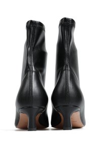 Czarne skórzane botki za kostkę o eleganckim, smukłym kształcie, z wąskim obcasem i widocznym przeszyciem wzdłuż tylnego szwu.