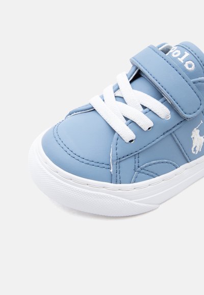 Ανοιχτό μπλε παιδικό αθλητικό παπούτσι με λευκά κορδόνια, λουράκι με βέλκρο, λευκή σόλα και κεντημένο λογότυπο στο πλάι.