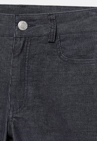 Pantaloni din denim închis, cu o textură canelată, prezentând un sistem de închidere cu un buton argintiu, o buzunar frontal și detalii de cusătură contrastante.
