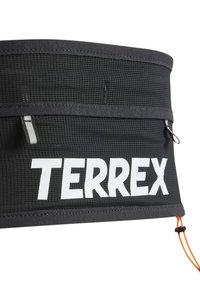 Svart Terrex hofteveske med teksturert stoff, med en fremtredende hvit logo, to glidelåslommer og en oransje snor for lukking.