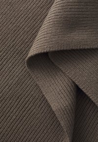 Textured brown fabric with parallel ribbed lines, featuring a soft, woven appearance and a folded edge revealing the inner layer.