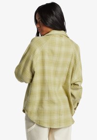 Grønt plaid skjorte med en afslappet pasform, lange ærmer og rundet kant. Fremstillet af et struktureret stof med et gittermønster.