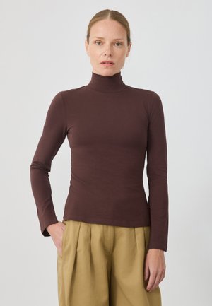 Burgunderfarbene Langarm-Turtleneck-Bluse aus weichem, elastischem Stoff mit tailliertem Schnitt und hohem Kragen, kombiniert mit hellbeigen, plissierten Hosen.