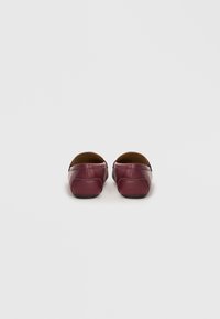 Bourgognefarvede lædersko med rund tå, minimal syning, glat tekstur og flade sorte såler. Set bagfra.