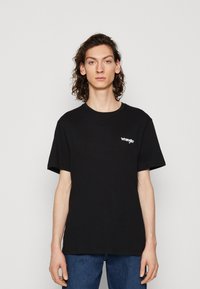 Čierne bavlnené tričko s krátkymi rukávmi a okrúhlym výstrihom, na hrudi s malým bielym logom "Wrangler". Jednoduchý, voľný strih.