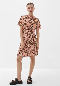 Korte mouwen roze jurk met bloemmotieven, elastische taille en gerimpelde zoom. Gecombineerd met zwarte platform sandalen met dubbele banden.