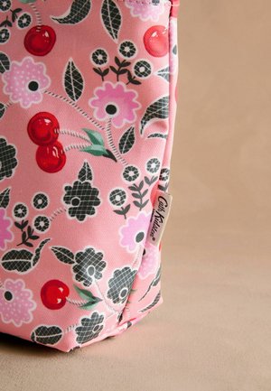 Pink fabric bag with floral and cherry patterns. Features contrasting black and green details, tag with "Cath Kidston" logo. Textured surface.