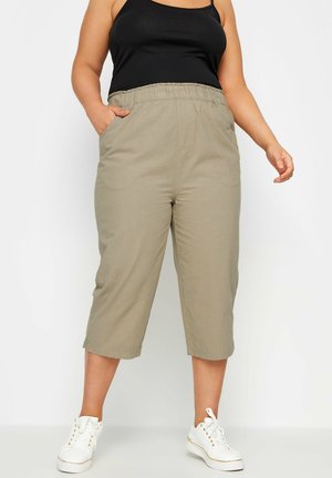 Khaki capri broek met een elastische tailleband en zijzakken, gemaakt van zachte stof. Gecombineerd met witte sneakers voor een casual look.