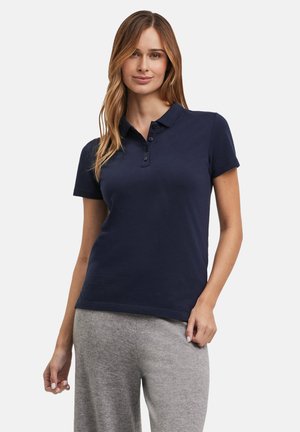 Camisa polo de color azul marino hecha de algodón, con cuello y tapeta de tres botones. Mangas cortas y un diseño ajustado con una textura suave.