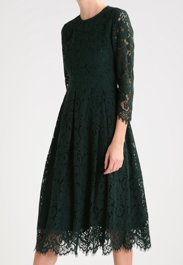 Robe en dentelle vert foncé avec des manches trois-quarts, un corsage ajusté et une jupe évasée. Un bord en dentelle à l'ourlet ajoute un détail raffiné.