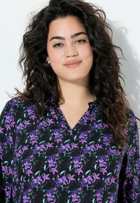 Black blouse featuring a floral pattern with purple and teal accents, v-neck design, and a loose fit with textured fabric.