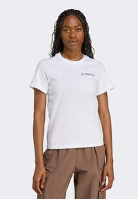 Camiseta blanca de manga corta con cuello redondo y logo gris "TERREX" en el lado izquierdo del pecho; tejido suave y ajuste estándar.