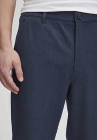 Navy blue dress pants made of a smooth fabric, featuring a single button closure and a flat front design with subtle texture.