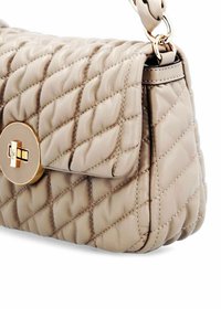 Beige quilted leren handtas met gouden draaivergrendeling en gevoerde riembevestiging, schuine zijaanzicht.