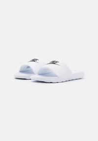 White Nike slide sandals with a smooth plastic upper, open toe design, and a black logo across the strap. Textured sole for grip.