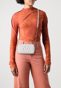 Crossbody bag in soft white leather, featuring embossed floral design, chain strap, rectangular shape, and smooth texture.