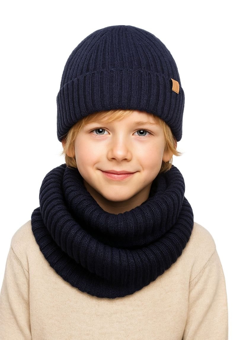 Navy knitted beanie with ribbed texture, paired with a matching ribbed infinity scarf, worn over a beige sweater.
