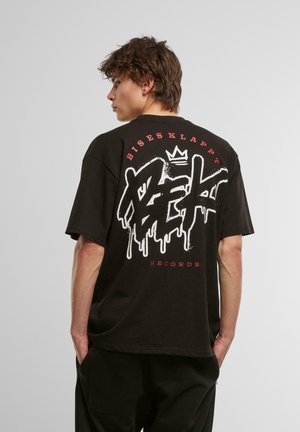Svart oversized t-skjorte med en stor hvit og rød graffiti-lignende logo på ryggen, med teksten "Bisesklappt Records."