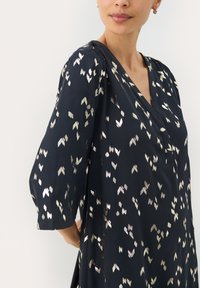 Navy-Kleid mit V-Ausschnitt und Dreiviertelärmeln, das metallische, blattähnliche Muster in Silber- und Goldtönen aufweist.