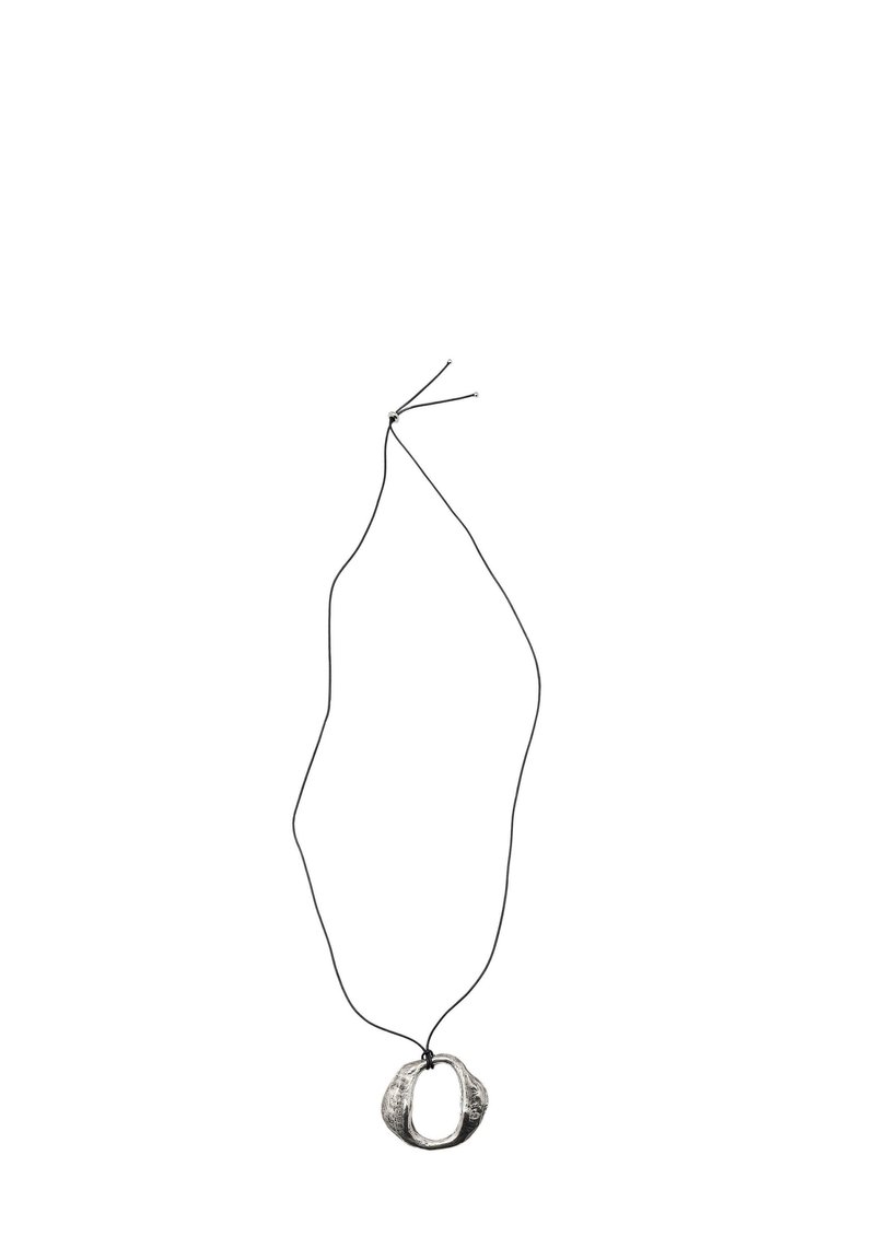 Collana pendente di colore argento con un design ovale organico, infilata su un sottile cordino nero. Il pendente ha una superficie testurizzata.
