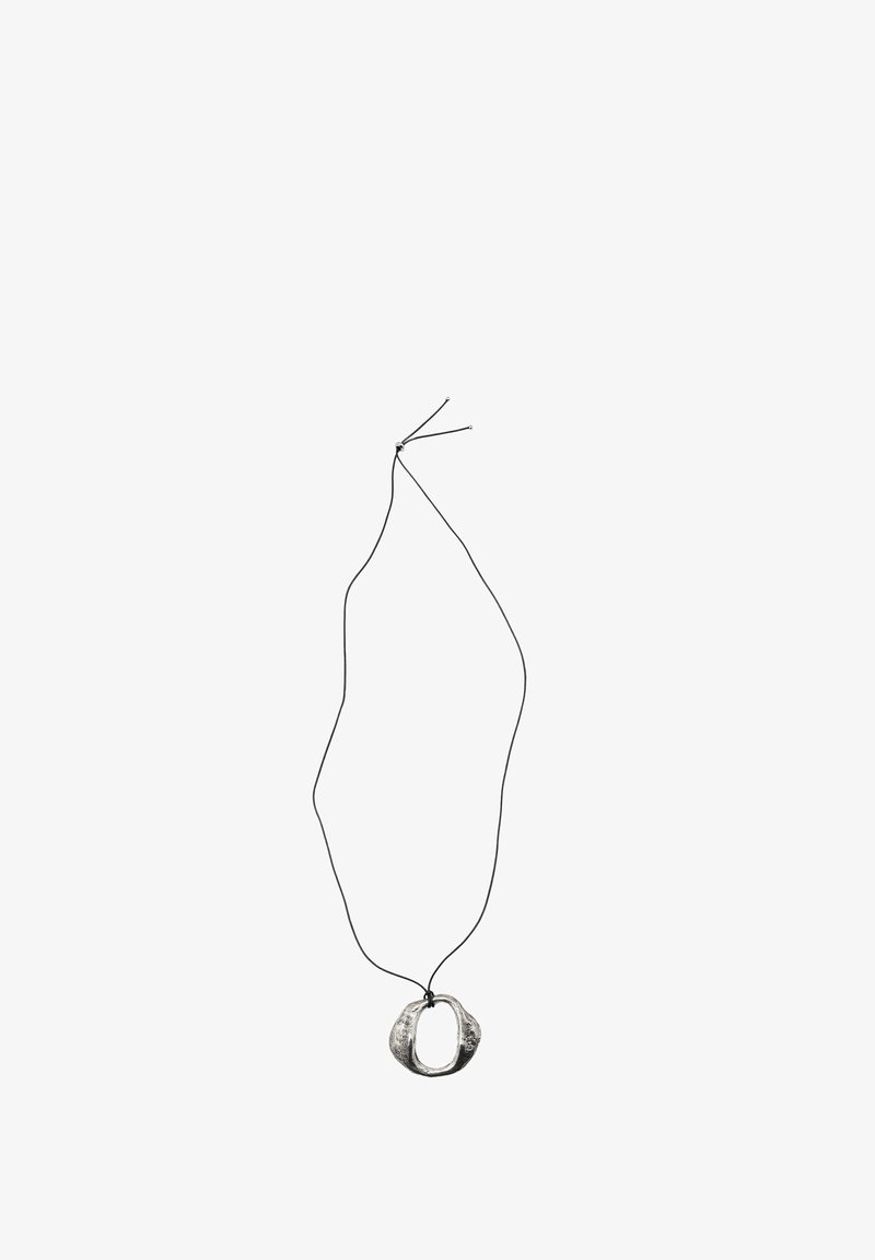 Collana pendente di colore argento con un design ovale organico, infilata su un sottile cordino nero. Il pendente ha una superficie testurizzata.