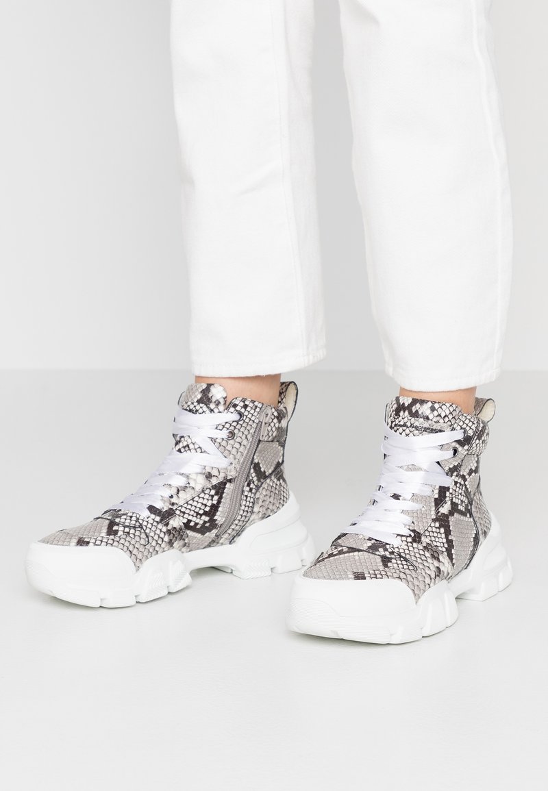 Wysokie sneakersy w szarym i czarnym wzorze węża, z białymi sznurowadłami oraz teksturowaną gumową podeszwą o masywnej sylwetce.