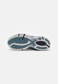 Semelle d'une chaussure de sport bleue et blanche montrant des motifs de bande de roulement texturés et des zones d'adhérence pour la course ou la marche en extérieur.