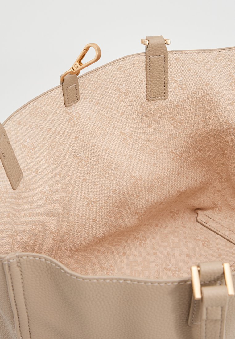 Intérieur d'un sac en cuir beige avec un motif texturé, des accessoires en ton doré et une doublure en tissu clair arborant un subtil motif floral.