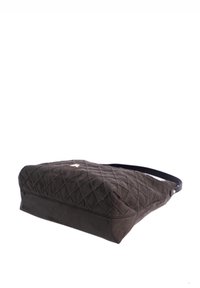 Bolso de tela negra acolchada con base plana, perfil delgado y una sola correa para el hombro. Cuenta con detalles en hardware de tono dorado.