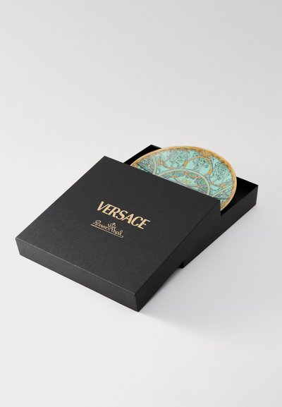 Versace dekoratīvs šķīvis melnā kastē. Šķīvja pamats ir tirkīzzils ar izsmalcinātām zelta un zaļām ziedu detaļām. Kaste rotāta ar zelta uzrakstiem.