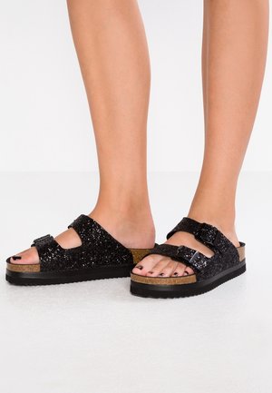 Czarne brokatowe sandały na płaskiej podeszwie z dwoma regulowanymi klamrami i korkową wkładką. Gruba czarna podeszwa z rowkowaną fakturą dla lepszej przyczepności.