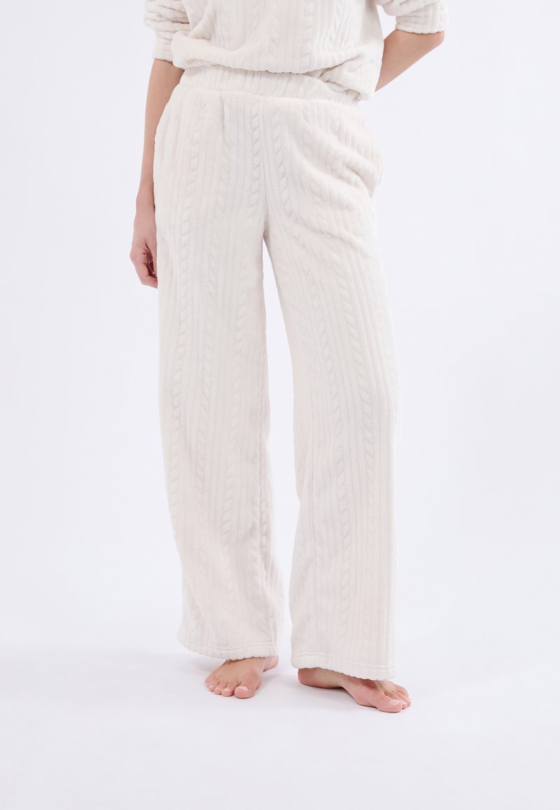 Pantalones de lounge de punto blanco con un tejido suave y texturizado. Presentan una cintura elástica y un diseño de pierna ancha.