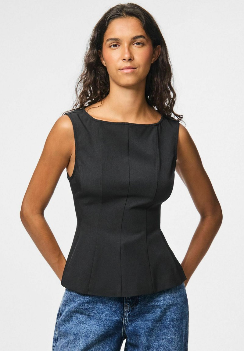 T-shirt sans manches noir avec un décolleté carré, forme structurée et coutures verticales ; associé à un jean en denim bleu.