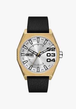 Hexagonal ur med en sølvfarvet urskive, guld tekstureret bezel, sorte timemarkeringsindikatorer og sort læderrem. Har fede tal ved 2, 3 og 4.