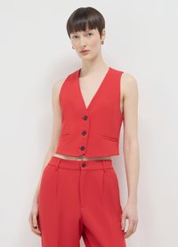 Veste rouge sans manches, courte, avec un décolleté en V profond, dotée de cinq boutons noirs et de deux poches avant. Tissu lisse, design structuré.