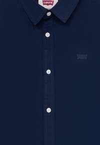 Marineblå Levi's knapp-up skjorte med hvite knapper og en liten tonal Levi's-logo på brystet.