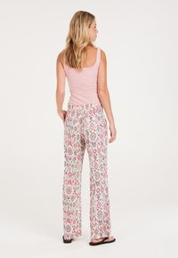 Roze geribbelde tanktop gecombineerd met een patroon van losse, elastische broek in het wit, met rode en blauwe bloemmotieven.