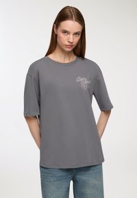 Szara bawełniana koszulka z okrągłym dekoltem i krótkimi rękawami, z jasnoróżową grafiką zawierającą napis "Ciao Amore."