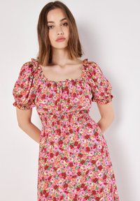 Blumenkleid mit pinkem Grundton und mehrfarbigen Blumen, quadratischer Ausschnitt, Puffärmel und gerafftem Taillenbund.