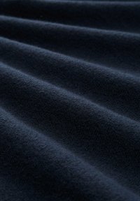 Marineblaue Fleece-Stoff mit weicher Textur, der subtile Wellen und unterschiedliche Tiefen aufweist, was ein glattes, einladendes Erscheinungsbild erzeugt.